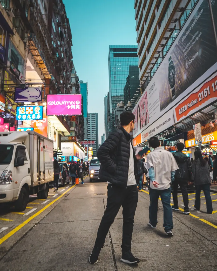 Gabriel com a mala atravessando uma rua de Hong Kong