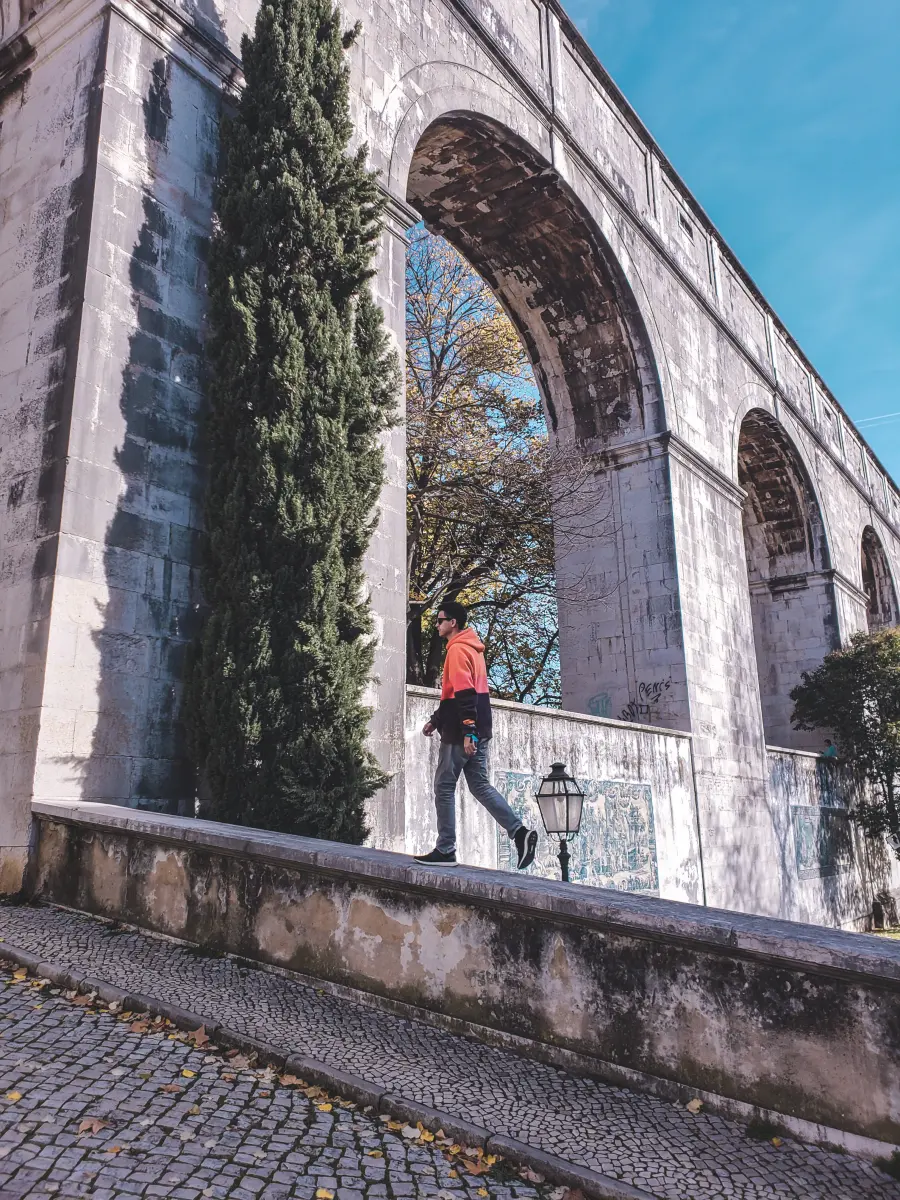 Gabriel caminhando sob os arcos de um aqueduto em Lisboa